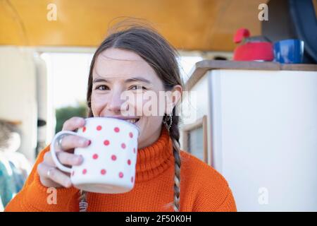 Portrait bonne jeune femme buvant du thé dans une camionnette de camping Banque D'Images