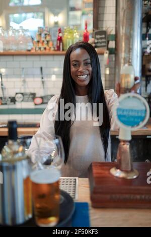 Portrait bonne jeune femme barman travaillant derrière le bar Banque D'Images
