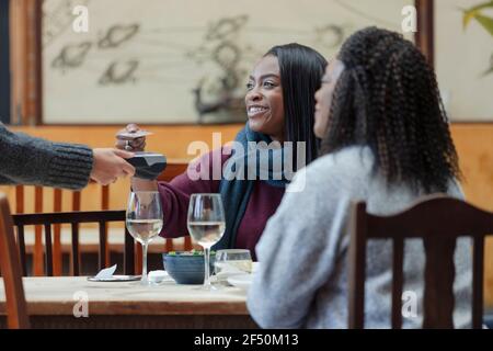 Mère et fille, serveuse payante avec carte à puce au café tableau Banque D'Images