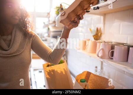 Femme déchargeant des produits d'épicerie dans la cuisine Banque D'Images