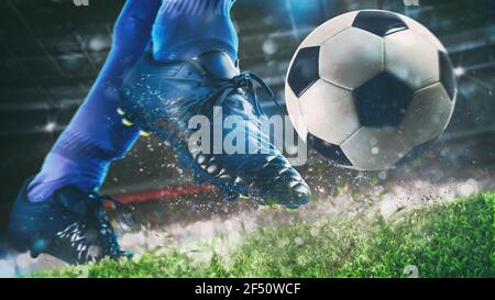 Scène de nuit football match avec gros plan d'une chaussure de soccer frapper la balle avec puissance Banque D'Images