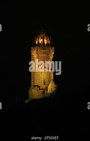 Le Monument national Wallace à Stirling, illuminé en jaune pendant la Journée nationale de réflexion, à l'occasion de l'anniversaire du premier confinement national pour prévenir la propagation du coronavirus. Date de la photo: Mardi 23 mars 2021. Banque D'Images