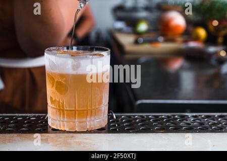 Un barman se dresse devant une boisson dans un verre de roche dépoli au bar. Banque D'Images