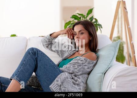 Femme caucasienne assise sur un canapé et souriante Banque D'Images