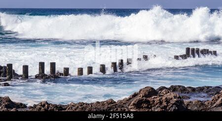 Gros plan de vagues mousseuse qui s'affronte contre une plage rocheuse par temps ensoleillé Banque D'Images