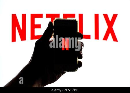 Dans cette illustration, l'application Netflix affichée sur Un écran de smartphone et un logo Netflix en arrière-plan Banque D'Images