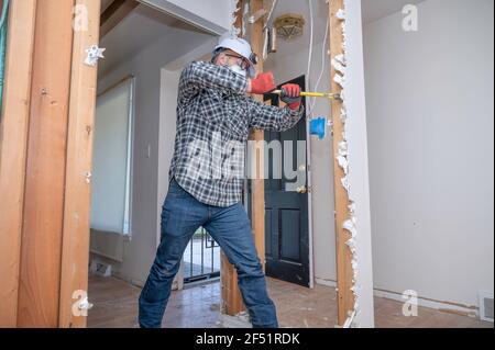 L'entrepreneur retire les panneaux de cloisons sèches pendant le projet de rénovation de la maison Banque D'Images