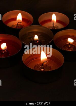 Bougies allumées - flamme. Petits radiateurs dans une pièce sombre. Quelques bougies colorées sur une table. Flamme de bougie sur fond sombre. Fête de Noël. Banque D'Images