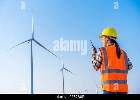 jeune femme ingénieur utilisant un talkie-walkie pour vérifier le système parc d'éoliennes Banque D'Images