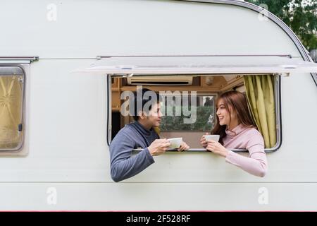 un jeune couple heureux qui boit du café à la fenêtre d'un campeur Camping camping-car Banque D'Images