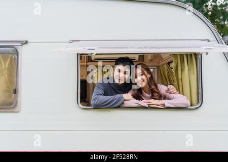 Un jeune couple heureux à la fenêtre d'une fourgonnette camping-car autocaravane Banque D'Images