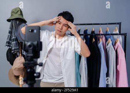 jeune homme stressé vendant des vêtements et des accessoires en ligne par streaming en direct sur smartphone, commerce électronique en ligne d'affaires à la maison Banque D'Images