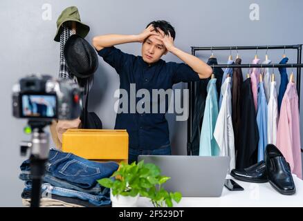 jeune homme stressé vendant des vêtements et des accessoires en ligne par caméra en direct streaming, affaires en ligne e-commerce à la maison Banque D'Images