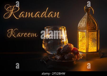 Ramadan Kareem, tradition religieuse musulmane, mois Saint dans l'Islam et Iftar concept thème avec un bol de dates, perles de prière, verre d'eau et arabe Banque D'Images