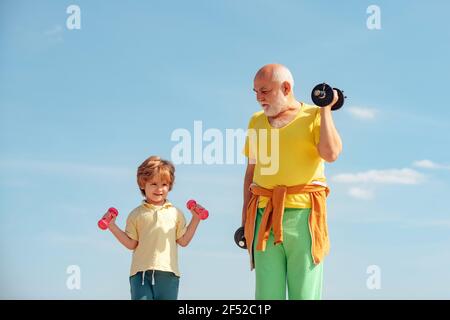 Homme et enfant âgés au club de santé familial. Un mode de vie sain. Grand-père et petit-fils avec haltères entre les mains. Sport pour les petits enfants. Banque D'Images