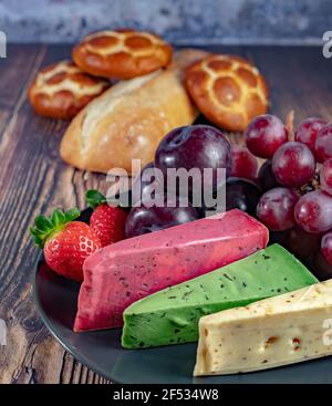 Vue de dessus de différents types de fromages néerlandais et néerlandais sur l'assiette et pain et fruits sur fond de bois. Banque D'Images