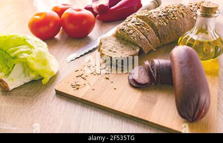 Petit déjeuner, saucisse avec fromage, confiture et pain.On a une table en bois.vue latérale lumière du matin. Banque D'Images