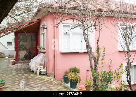 La vieille maison rose est dans les derniers jours de l'hiver. Les arbres sont encore secs. Avec deux étages et un jardin. Banque D'Images