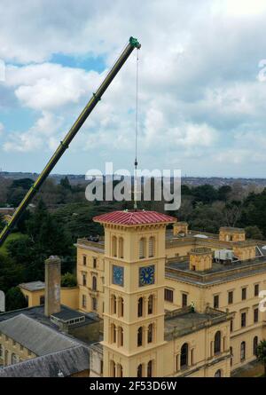 Des travailleurs de spécialistes en bâtiments historiques, G J Banks et Island Cranes, installent le weathervane victorien récemment restauré sur la tour d'horloge de 90 mètres à la maison Osborne du patrimoine anglais, à East Cowes, sur l'île de Wight, en achevant une restauration de deux ans de la girouette après qu'elle ait été endommagée pendant une tempête. Date de la photo: Mercredi 24 mars 2021. Banque D'Images