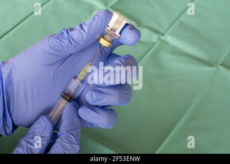 Main d'un professionnel de la santé dans un gant violet préparant une seringue devant un chiffon chirurgical. Gros plan d'une main de chirurgien avec un vaccin. Une seringue avec TH Banque D'Images