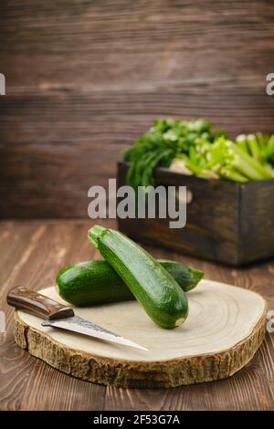 Courgettes vert frais sur une planche à découper en bois (priorité au premier plan) Banque D'Images