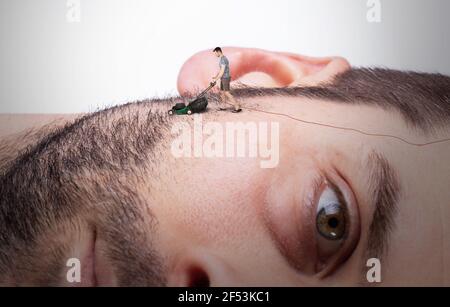 Homme équipé d'une tondeuse à gazon miniature se raser son visage géant, concept d'entretien Banque D'Images