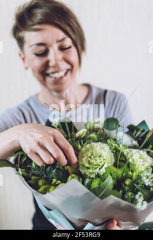 Cours de conception florale en ligne, entreprise floriste, petite entreprise, organisation florale, tendances floristes. Fleuriste femme montre la classe de maître, tutoriel sur Banque D'Images