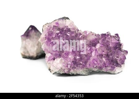 Deux améthystes violets bruts forment un amas de cristaux isolés sur fond blanc. Grande drase étincelante et petite pierre précieuse. Banque D'Images