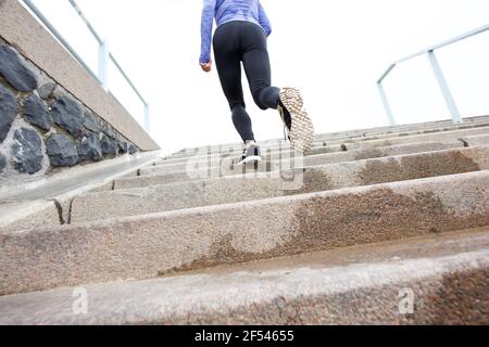 Portrait arrière à angle bas de la coureuse sur un escalier humide extérieur Banque D'Images
