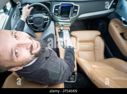 Drôle grand angle d'un conducteur mâle dans une voiture de luxe Banque D'Images
