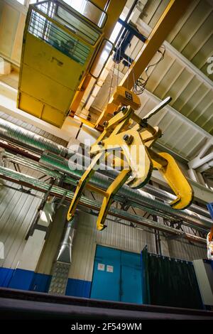 Ekibastuz, région de Pavlodar, Kazakhstan - 28 mai 2012 : usine de construction de chariots. Main mécanique jaune de la grue à poutre et opérateur en cabine. Banque D'Images