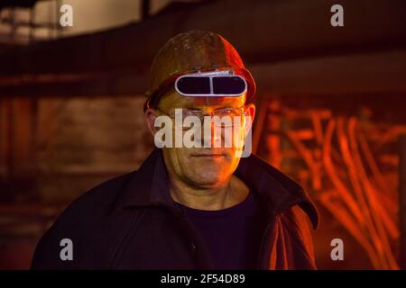 Aksu, région de Pavlodar, Kazakhstan - mai 29 2012 : usine d'alliages métalliques. Portrait du métallurgiste sur fond lumineux orange du four. Banque D'Images