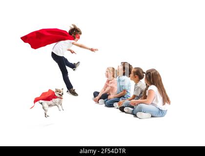 Enfant prétendant être un super-héros avec son super chien et des amis assis autour Banque D'Images