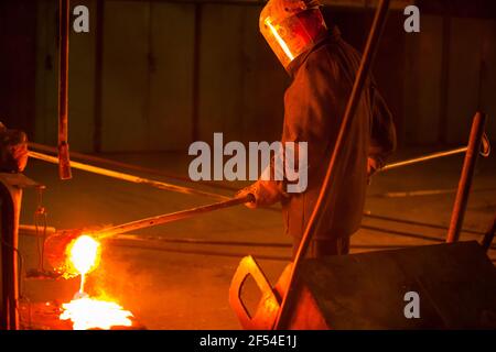 Aksu, région de Pavlodar, Kazakhstan - mai 29 2012 : usine d'alliages métalliques. Métallurgiste dans le masque de protection en verre testant le métal en fusion. Banque D'Images