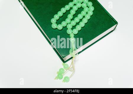 Les perles roses islamiques de couleur verte se trouvent sur le Saint Livre des musulmans sur fond blanc Banque D'Images