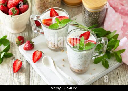 Concept de saine alimentation petit déjeuner. Granola maison avec fraise, yaourt, graines de chia, granola maison et baies fraîches sur une table en bois. Banque D'Images