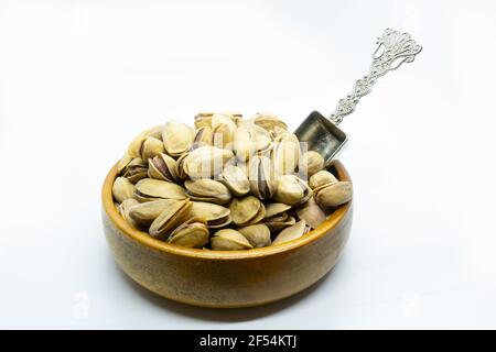 Pistaches en noix de carapace dans un bol avec cuillère isolée Banque D'Images