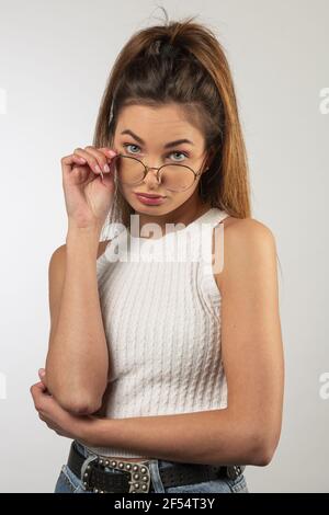 portrait naturel de modèle italien frais , posant sur blanc , regardant dans le visage de fabrication de l'appareil photo , sur ses lunettes. expression douce en colère Banque D'Images