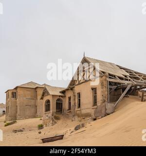 Vue latérale avec beaucoup de sable à la maison Lehrer À German Kolmanskop - Kolmannskuppe ville fantôme en Namibie avec les bâtiments abandonnés Banque D'Images