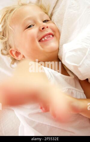 Gros plan portrait d'une petite fille couchée sur le lit et souriant Banque D'Images