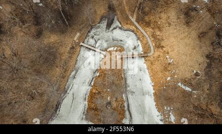 Une prise de vue aérienne au-dessus d'un parc avec un étang avec un petit pont. C'est une belle journée d'automne d'une vue d'oiseau. L'étang est gelé. Tir de drone Banque D'Images