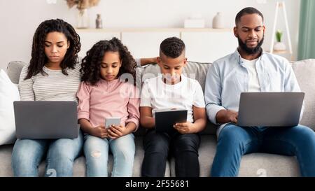 Famille afro-américaine ciblée tenant et utilisant des gadgets Banque D'Images