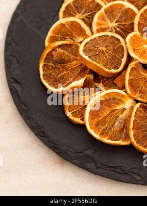Tranches d'orange déshydratée sur pierre noire. Mise au point sélective. Banque D'Images
