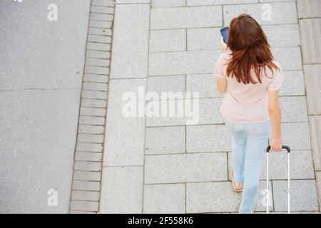 Vue de dessus portrait d'une femme voyageur avec sac à pied la rue et en utilisant le téléphone mobile Banque D'Images