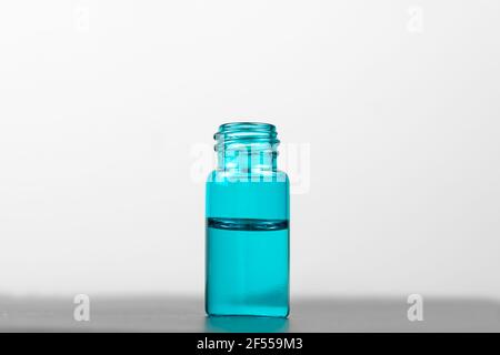 Gros plan d'une bouteille de sérum turquoise sur fond blanc. Concept de cosmétologie, médecine Banque D'Images