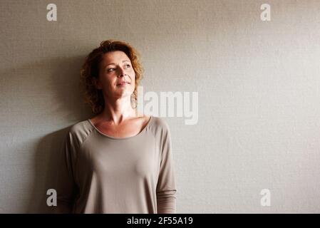 Portrait d'une femme avec des cheveux bouclés pendu mur vers l'intérieur contemplation Banque D'Images