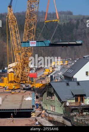 Amtsberg, Allemagne. 24 mars 2021. Une grue est utilisée pour soulever une section pour un pont ferroviaire au-dessus de la rivière Zwönitz dans la voie. La structure pèse au total 180 tonnes, mesure 37 mètres de long, 11 mètres de large et est placée sur les butées en deux sections distinctes. Le pont fait partie de la ligne de chemin de fer entre Aue et la gare centrale de Chemnitz. Selon le Verkehrsverbund Mittelsachsen (VMS), une date d'achèvement n'a pas encore été fixée en raison des conditions de corona. Credit: Hendrik Schmidt/dpa-Zentralbild/ZB/dpa/Alay Live News Banque D'Images