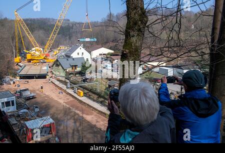 Amtsberg, Allemagne. 24 mars 2021. Une grue est utilisée pour soulever une section pour un pont ferroviaire sur la rivière Zwönitz dans la voie; les spectateurs regardent et prennent des photos. La structure pèse au total 180 tonnes, mesure 37 mètres de long, 11 mètres de large et est placée sur les butées en deux sections distinctes. Le pont fait partie de la ligne de chemin de fer entre Aue et la gare centrale de Chemnitz. Selon le Verkehrsverbund Mittelsachsen (VMS), une date d'achèvement n'a pas encore été fixée en raison des conditions de corona. Credit: Hendrik Schmidt/dpa-Zentralbild/ZB/dpa/Alay Live News Banque D'Images