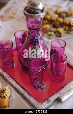 Magnifique ensemble arabe de six verres en violet fumé verre argenté et détails colorés reposant sur un assorti plateau argenté et rouge Banque D'Images