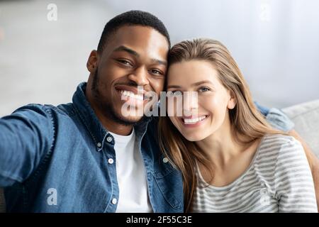 Heureux couple interracial prenant le selfie ensemble à la maison Banque D'Images